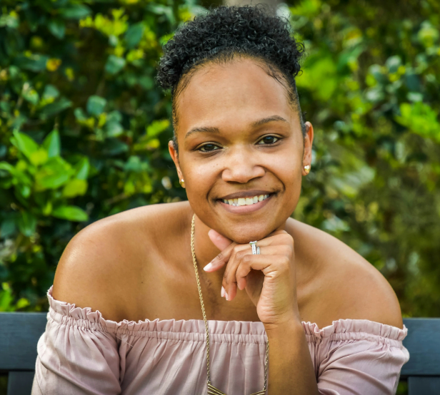 Une jeune femme souriante devant l'appareil photo.