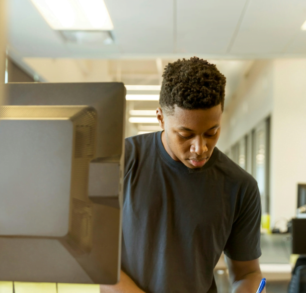 Un jeune homme prenant des notes devant son ordinateur.